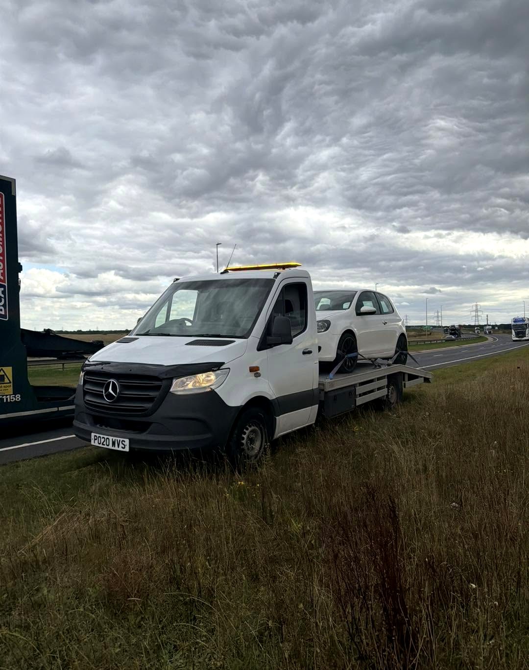 HC Recoverys Mercedes truck with a white hatchback loaded on the A-road