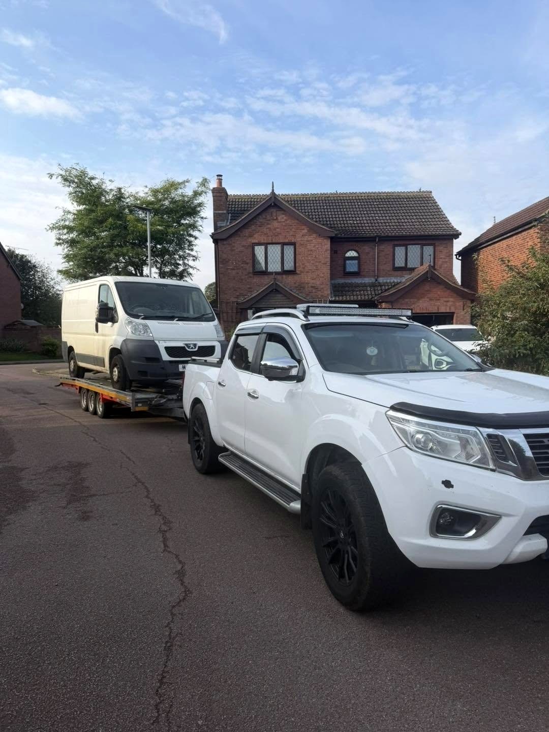 White pickup towing a Peugeot van on a car transporter