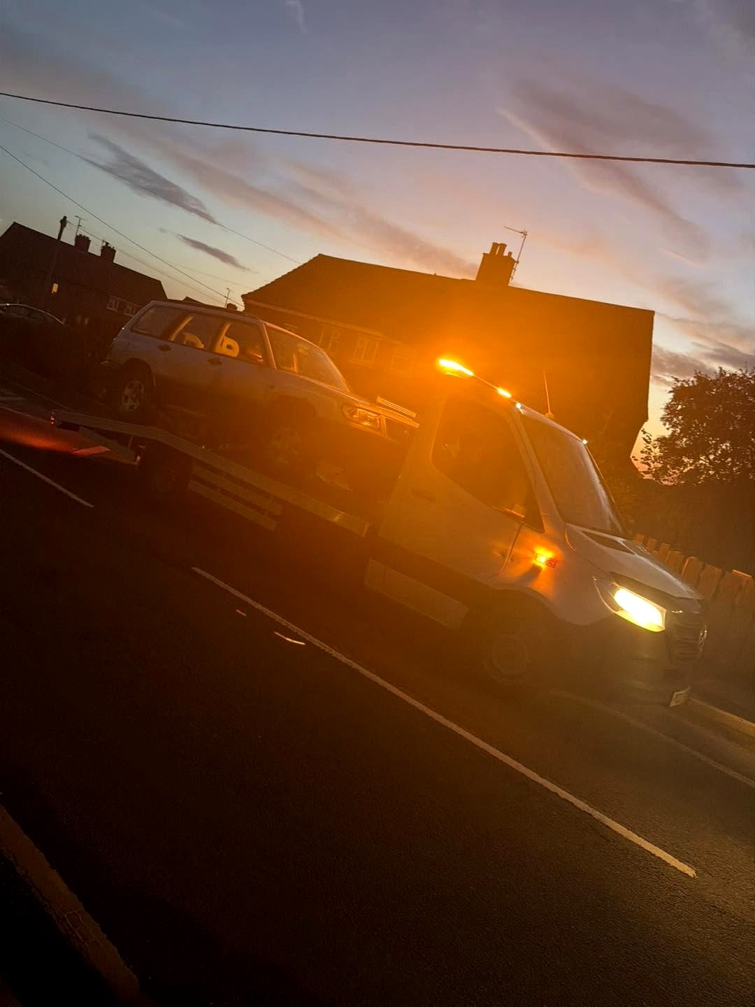 HC Recoverys truck at dusk with amber lights and an SUV on the bed