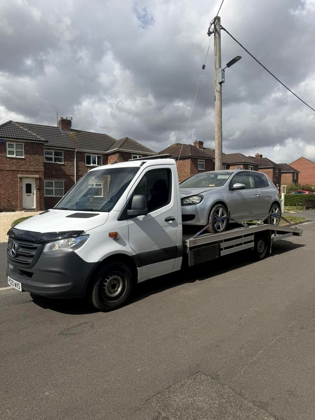 HC Recoverys truck with a silver hatchback loaded on a residential street