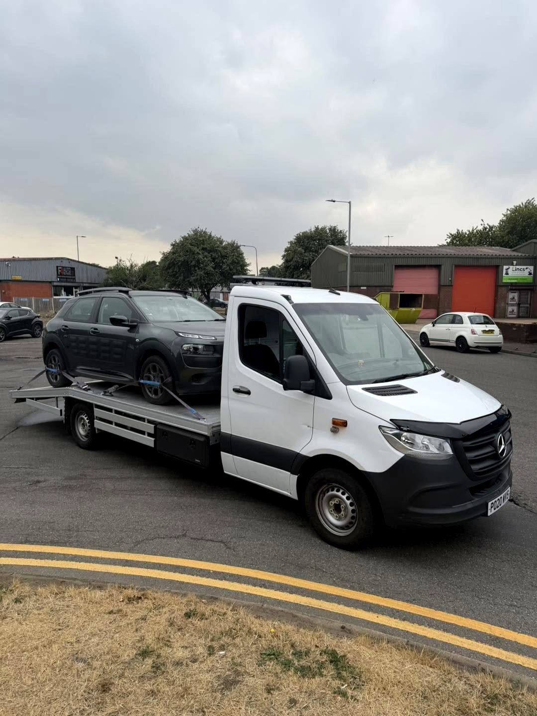 Mercedes recovery truck with a Citroen Cactus strapped on the bed